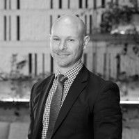A man in a suit and tie is smiling in a black and white photo.