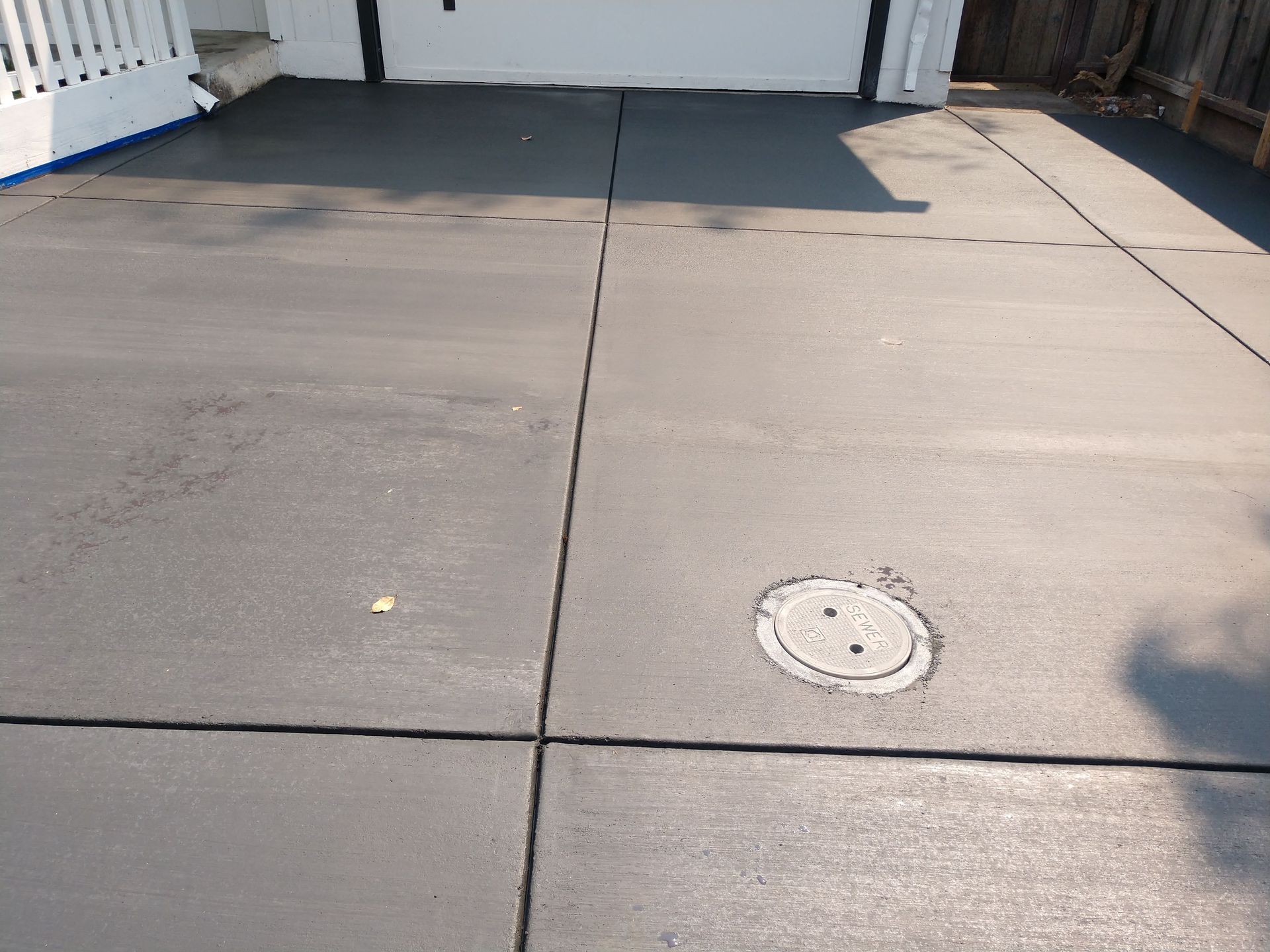 A gray concrete driveway with a manhole cover in the middle