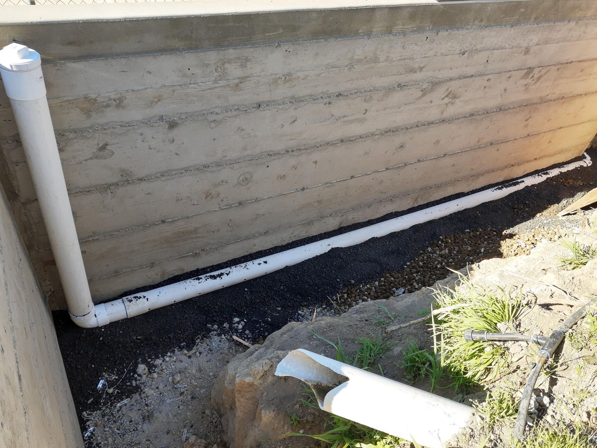 A concrete wall with white pipes coming out of it