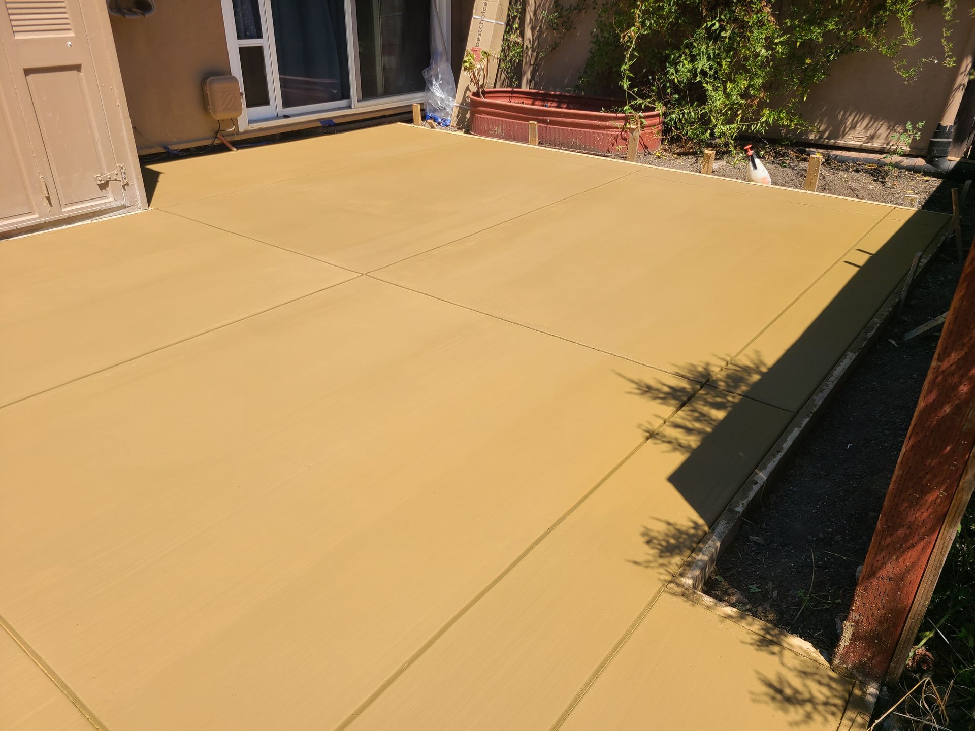 A yellow concrete patio with a sliding glass door in the background.