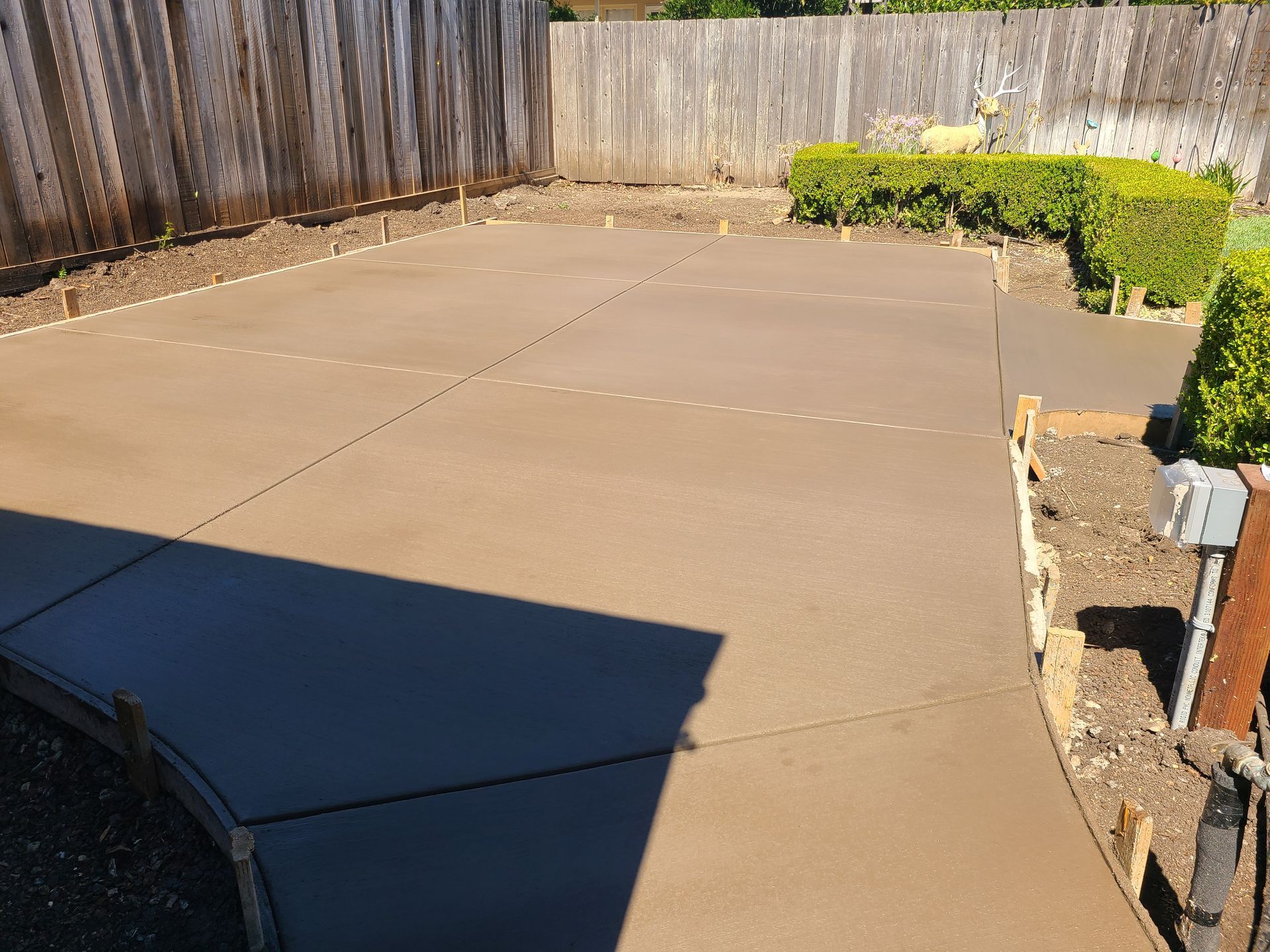 A concrete driveway with a wooden fence in the background.