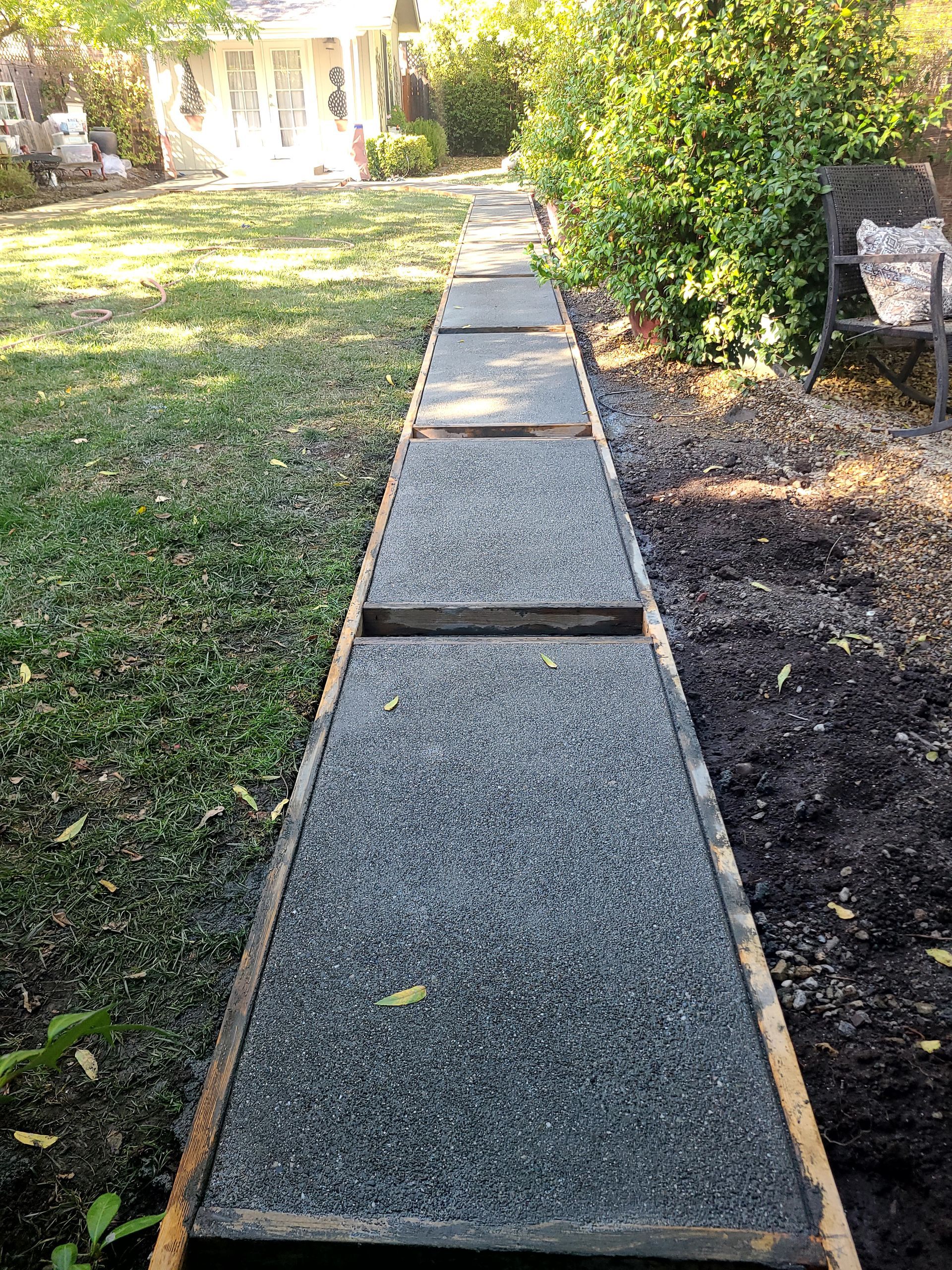 A walkway is being built in the backyard of a house.