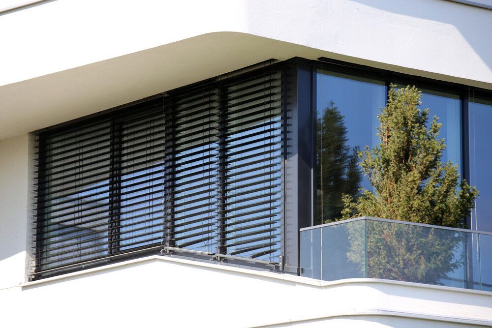 A Modern House With a Balcony and a Large Window With Blinds — Lismore Blinds in North Lismore, NSW
