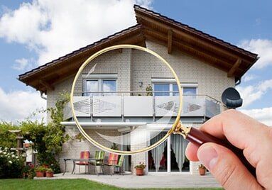 Hand With Magnifying Glass Over House — Leaking Wall Crack Repair in Buffalo, NY