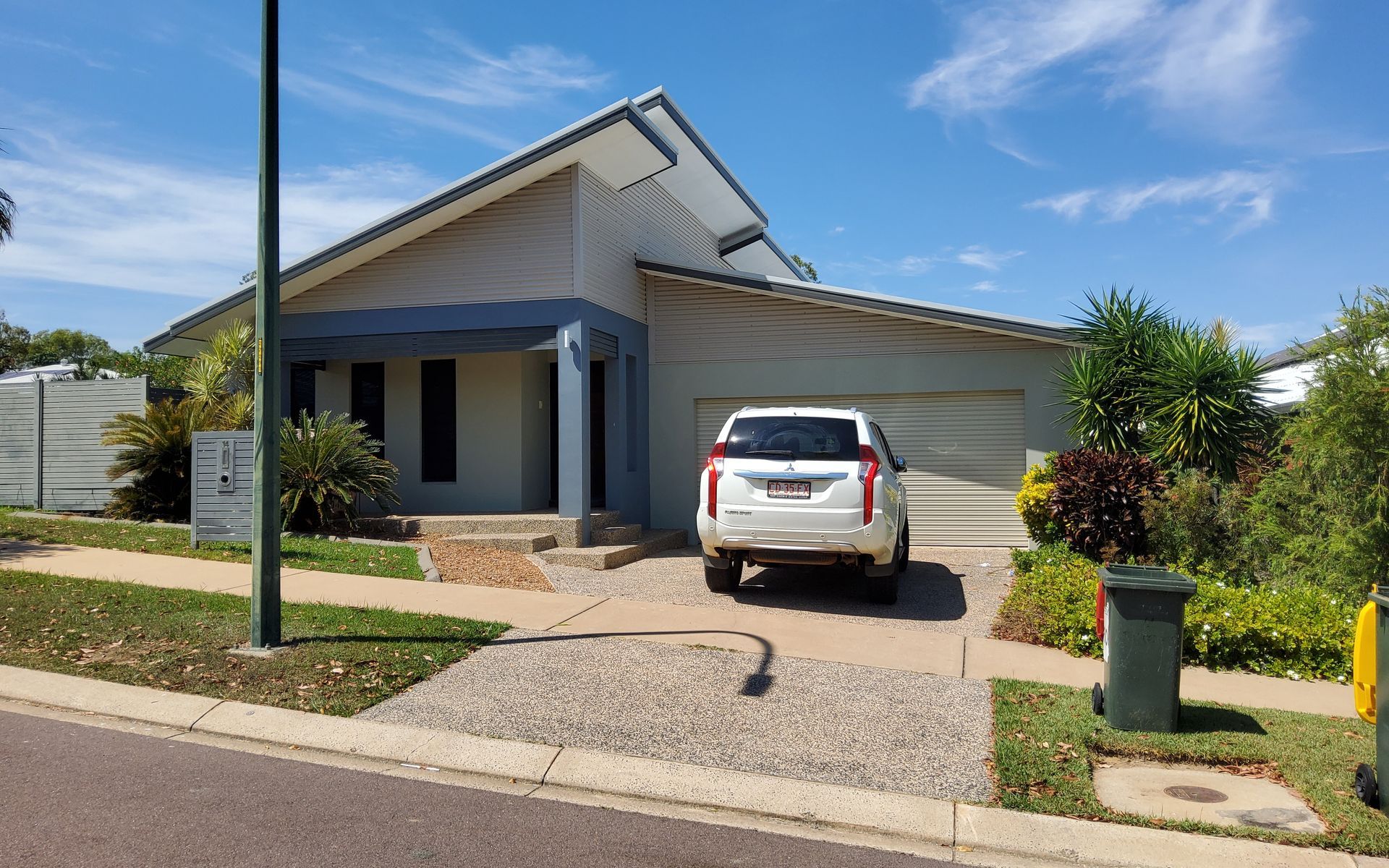 A Modern House With a White Car Parked in the Driveway on a Sunny Day — Neil Griffiths Rendering in Berry Springs, NT