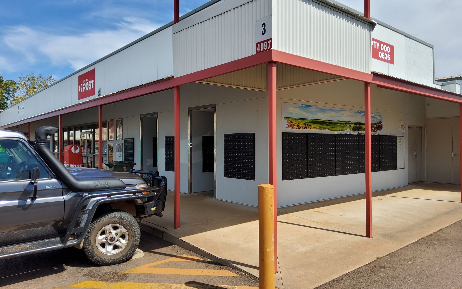 Grey Building With Red Awning, Post Office Boxes, a 4x4 Vehicle, and a Sign That Reads Post Office  — Neil Griffiths Rendering in Berry Springs, NT