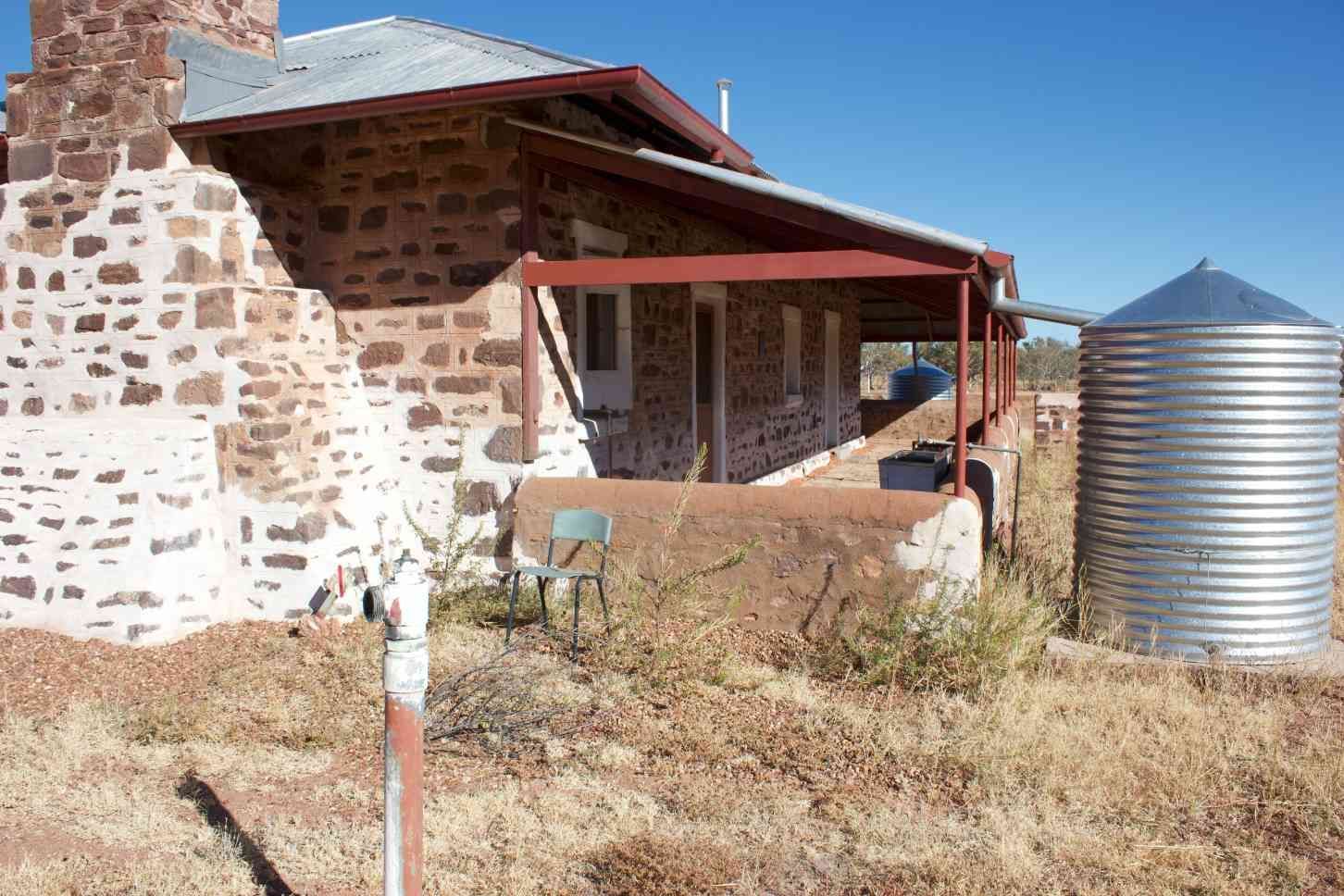 Stone House With a Red-roofed Porch and Metal Water Tank — Neil Griffiths Rendering in Berry Springs, NT