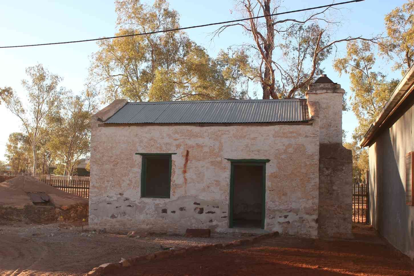 Old Weathered Stone Building With a Metal Roof, Green-framed Windows, and a Brick Chimney — Neil Griffiths Rendering in Berry Springs, NT