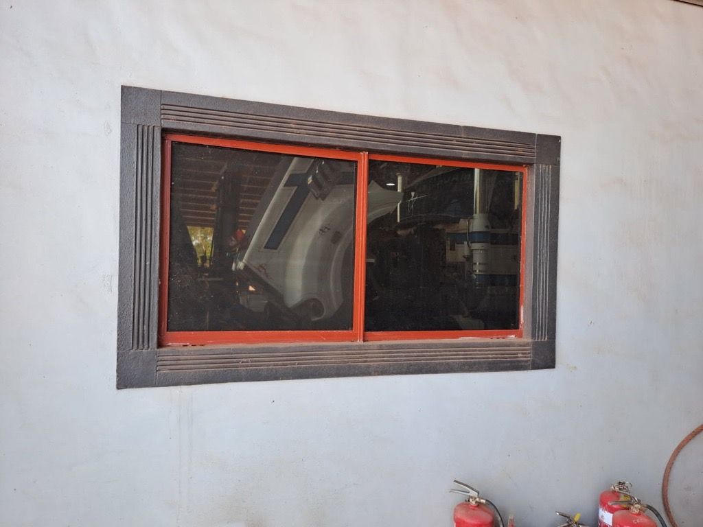 Window in a gray wall, red frame, dark screen, and ornate dark gray trim  — Neil Griffiths Rendering in Berry Springs, NT