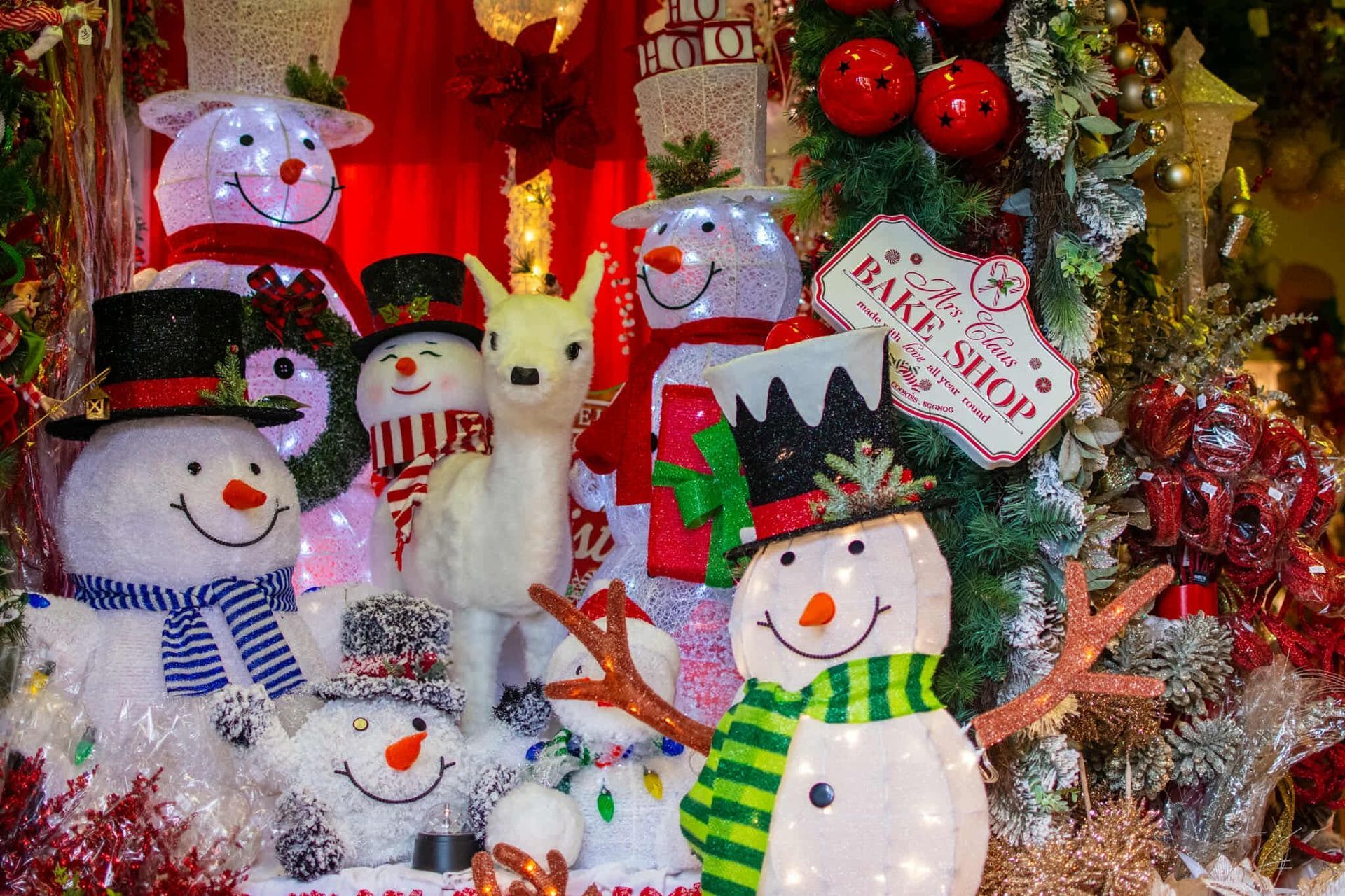 A display of christmas decorations including snowmen and a deer.