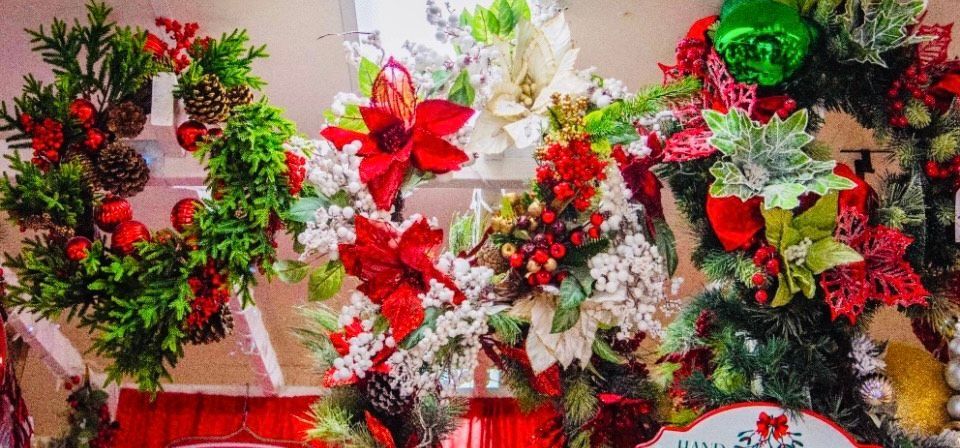 A bunch of christmas wreaths are hanging on a wall.