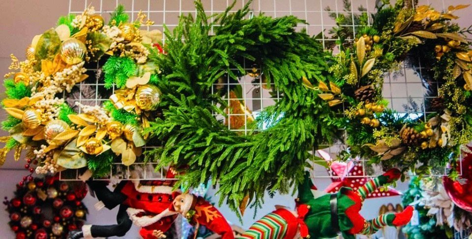 A bunch of christmas wreaths are hanging on a wall.