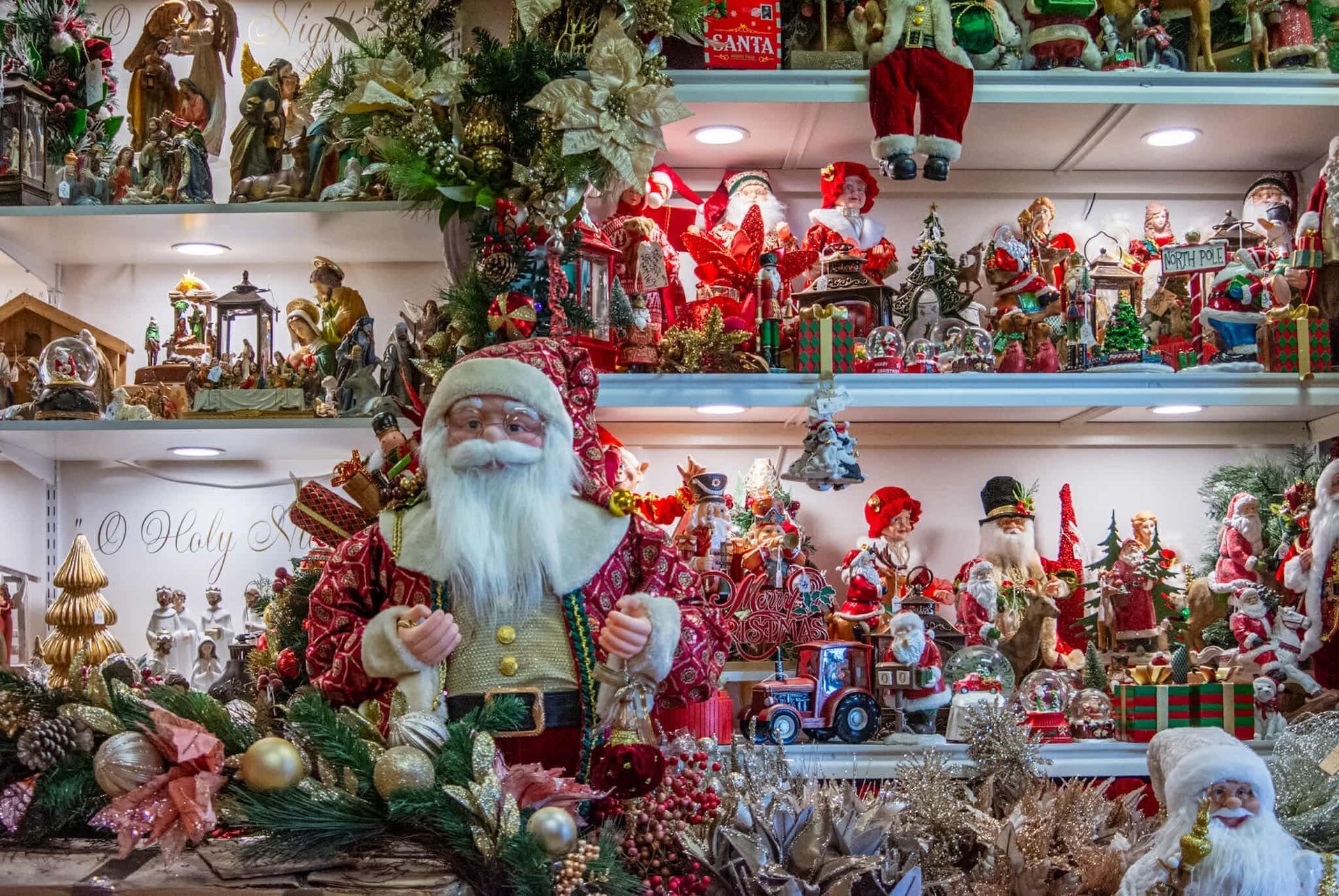 A shelf filled with lots of christmas decorations and a statue of santa claus.