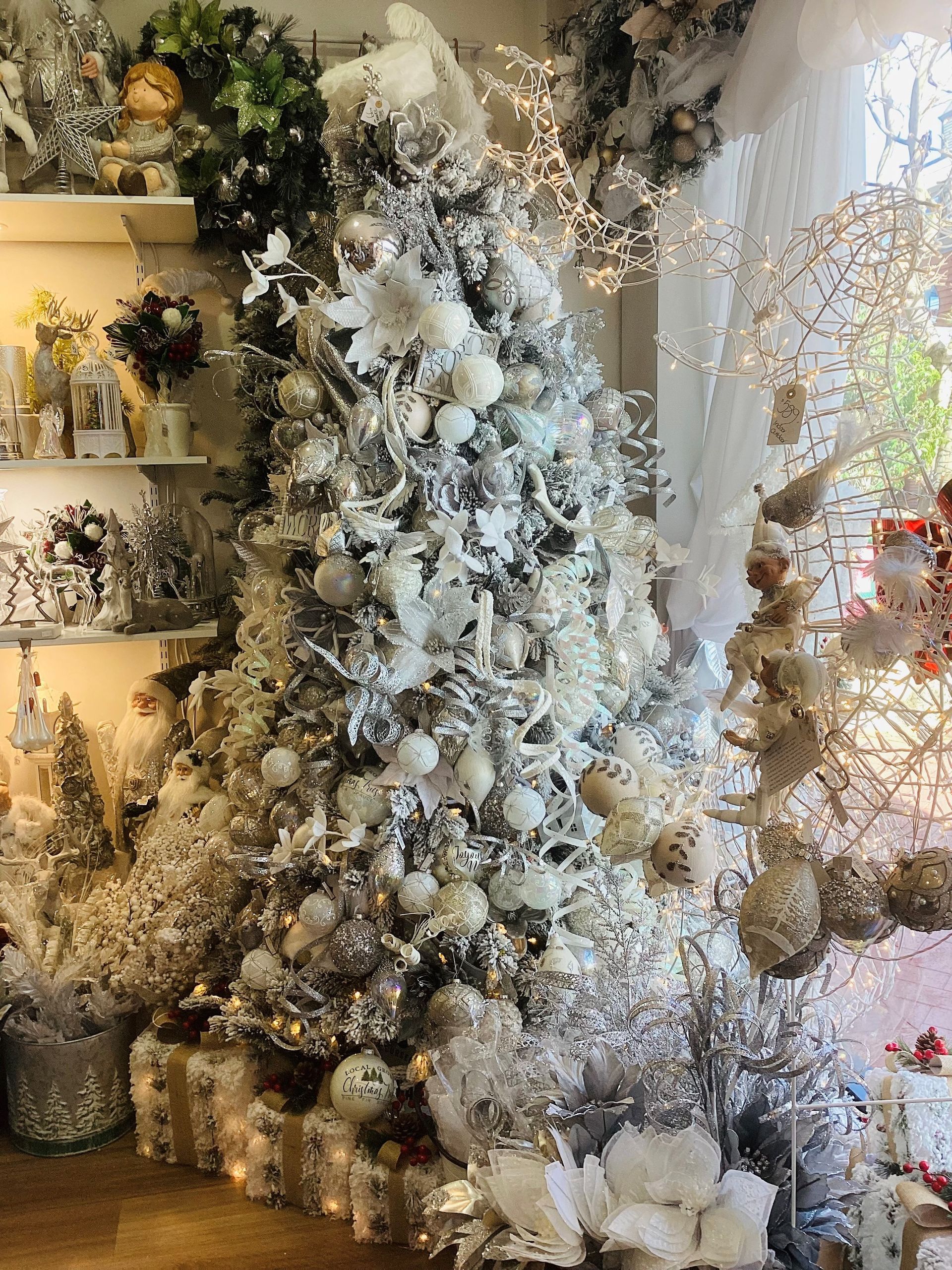 A white christmas tree is sitting in a room surrounded by christmas decorations.