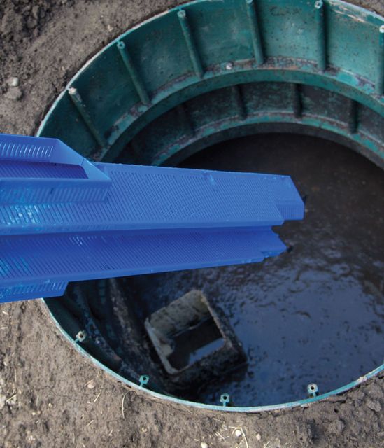 a blue filter is being returned to a septic tank after being cleaned.