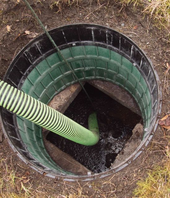 a green hose is being used to pump water out of a septic tank.