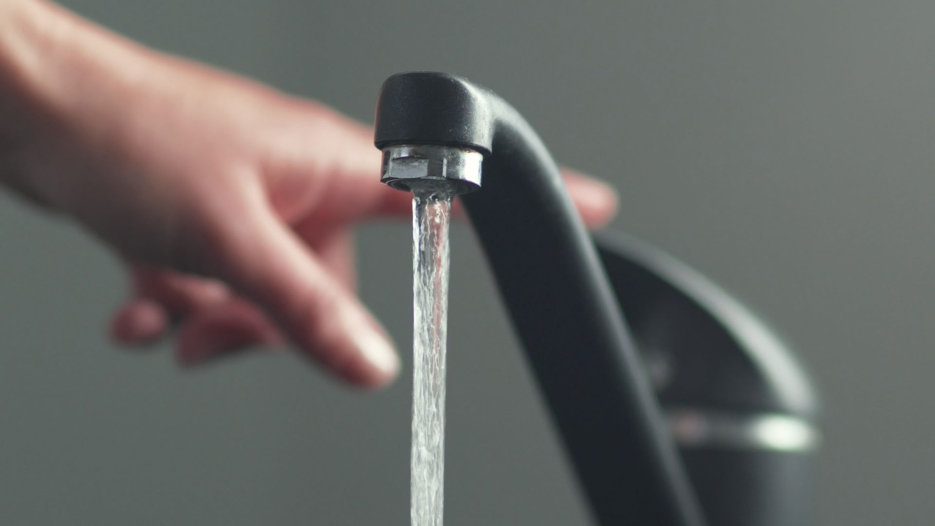 a person is opening a faucet with water running out of it.