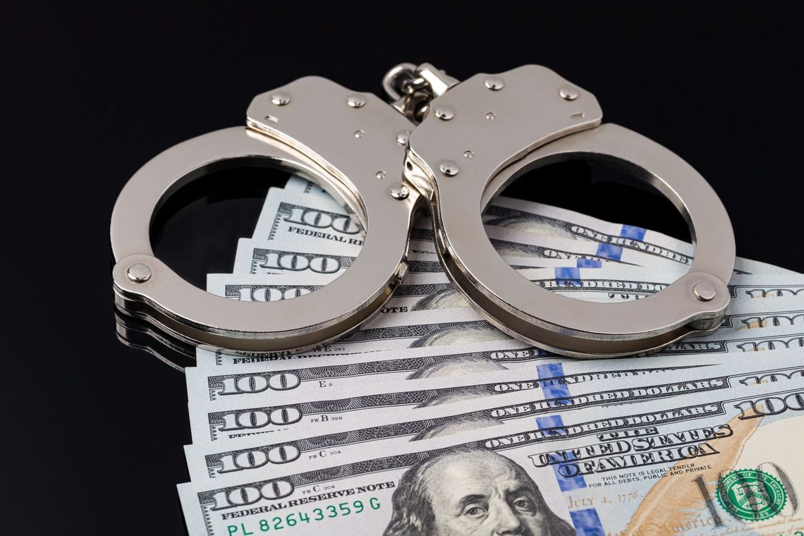 a pair of handcuffs sitting on top of a pile of money