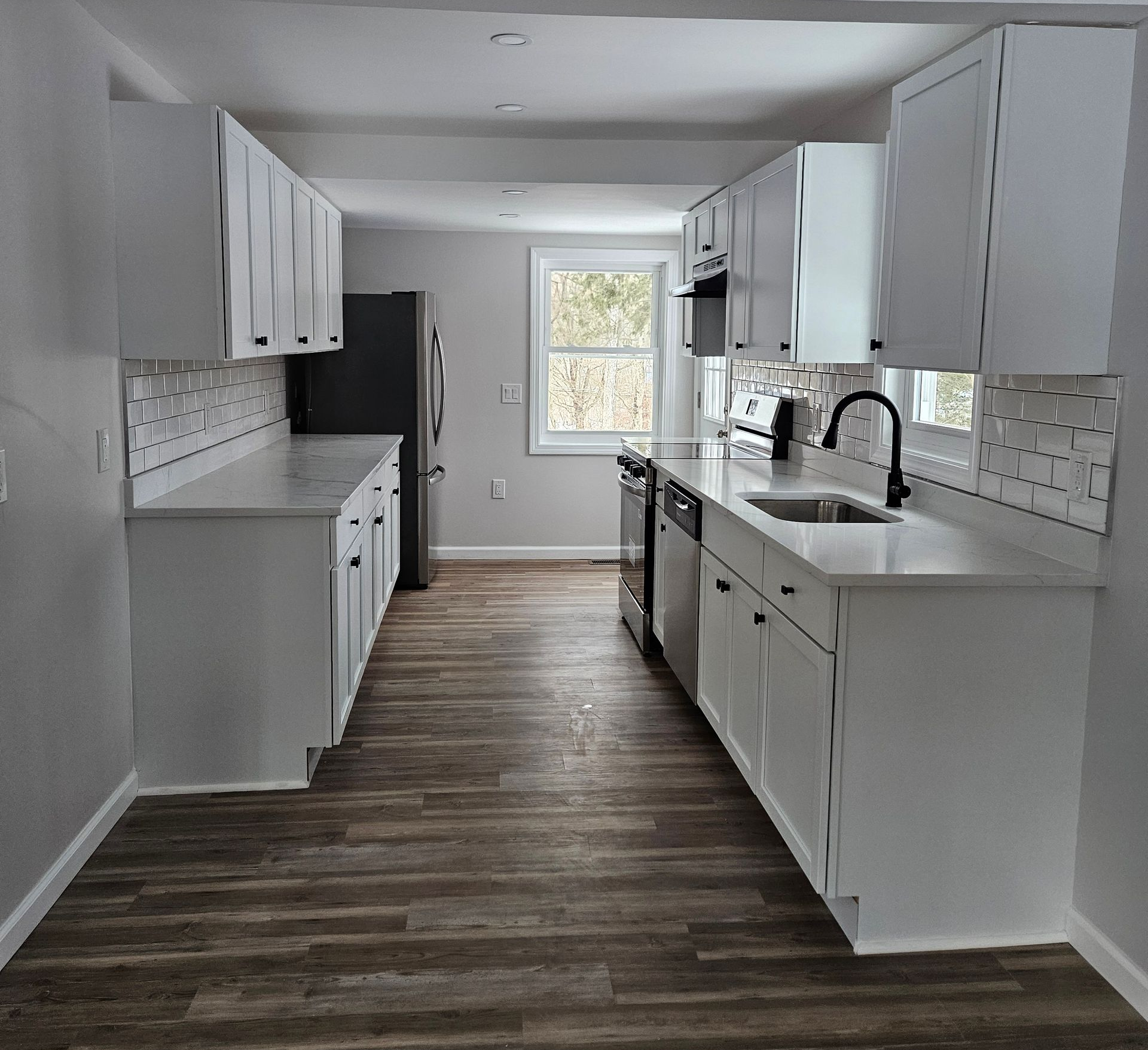 A kitchen under construction with white cabinets and wooden counter tops.
