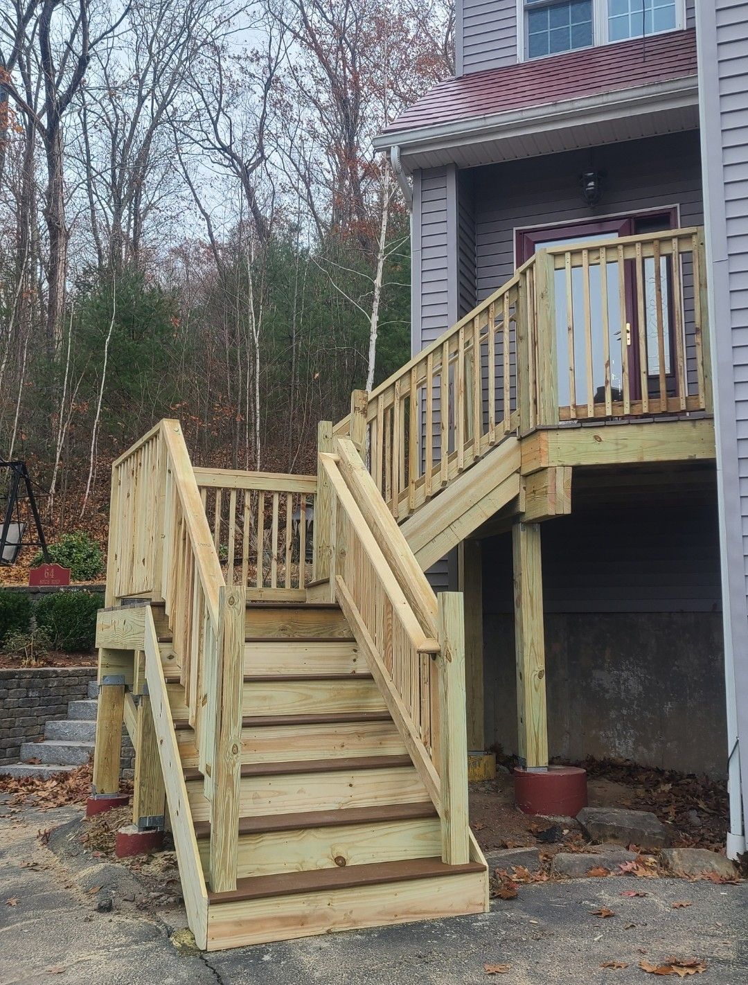 Wooden exterior stairs leading to a building's upper level. The steps are light brown, against a gray building.