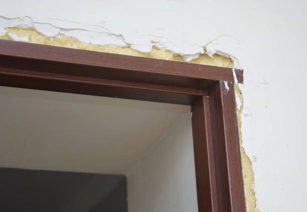 Brown door frame with peeling white wall paint above.