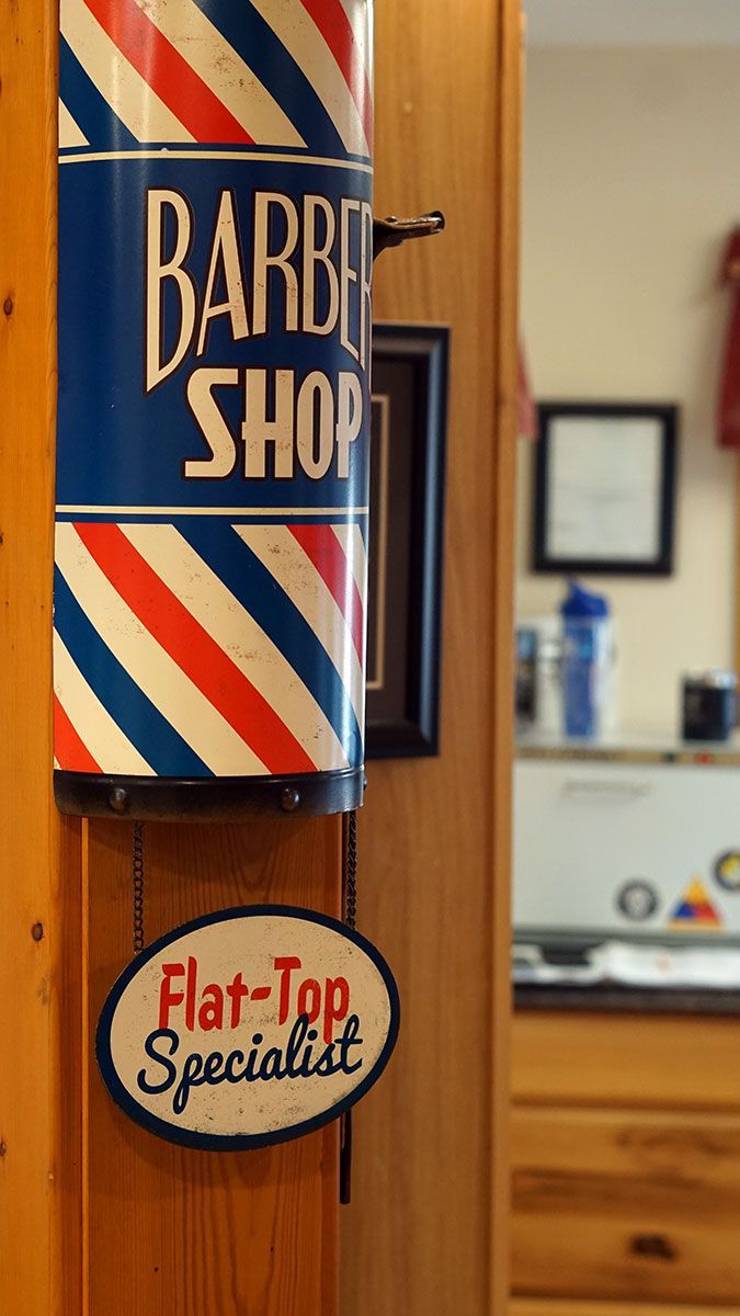 An antique red, white, and blue barber pole sign on the wall of a traditional barber shop.