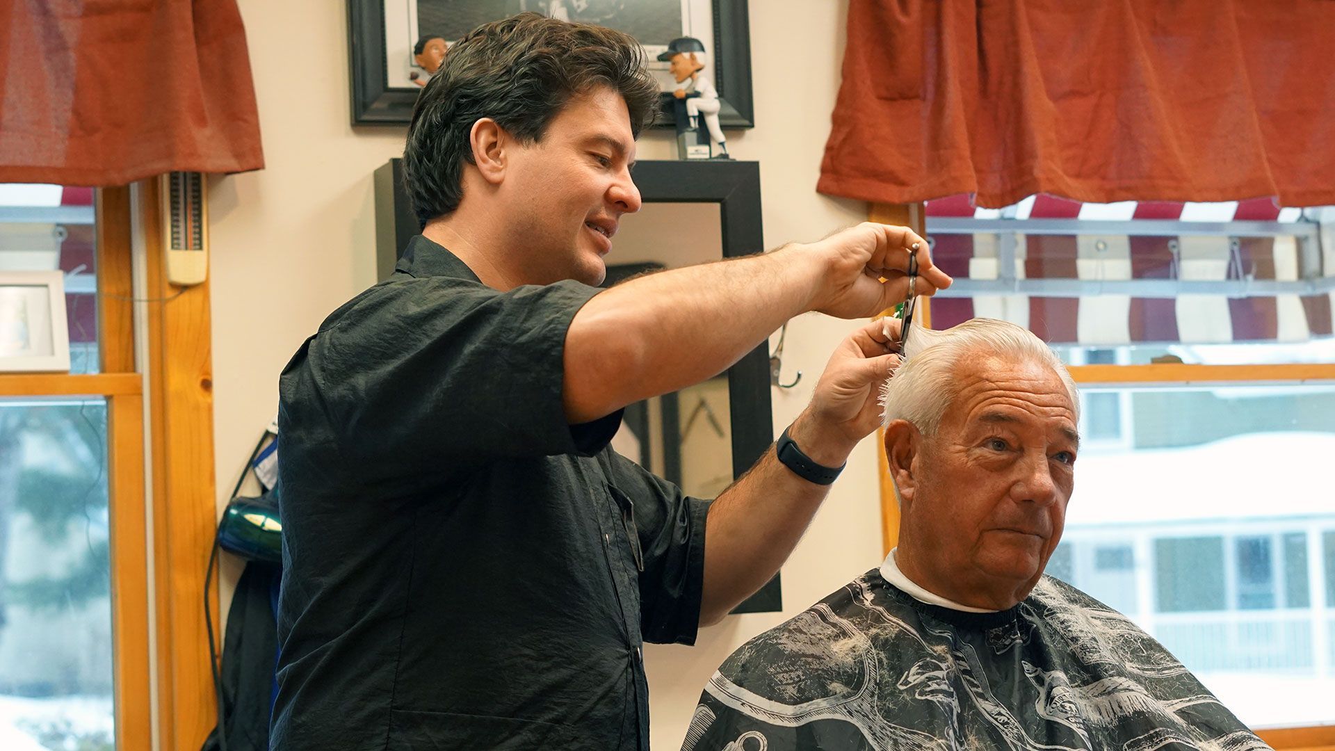 An older gentleman receives a quality haircut from a professional barber while engaging in light conversation.