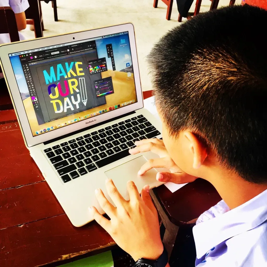 A man is typing on a laptop that says make our day
