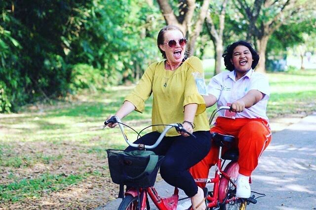 Two women are riding tandem bicycles in a park.