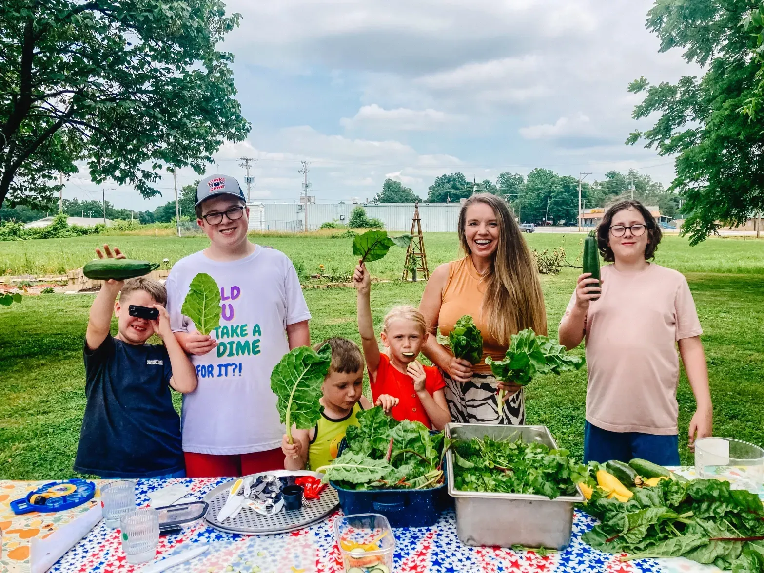 A group of people are standing around a table holding vegetables.