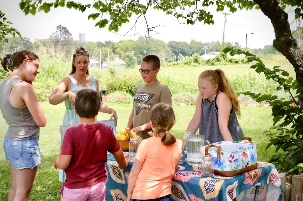 A group of children are standing around a table in a park.