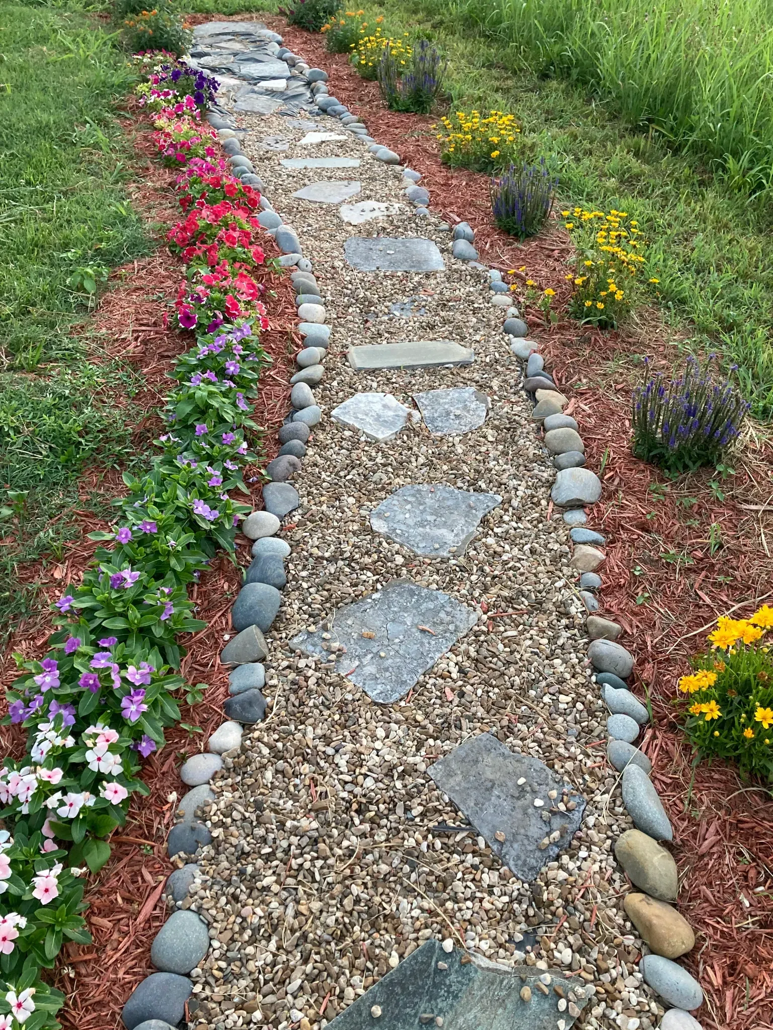 A stone walkway surrounded by flowers in a garden.