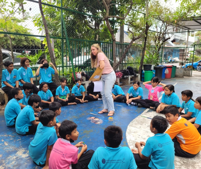 A woman is giving a presentation to a group of children
