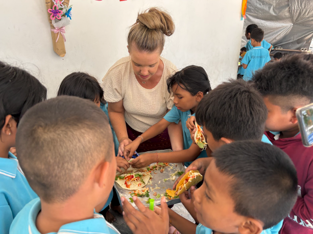 A woman is surrounded by children eating pizza