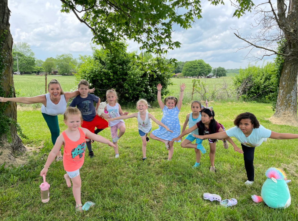 A group of young girls are doing yoga poses in the grass.