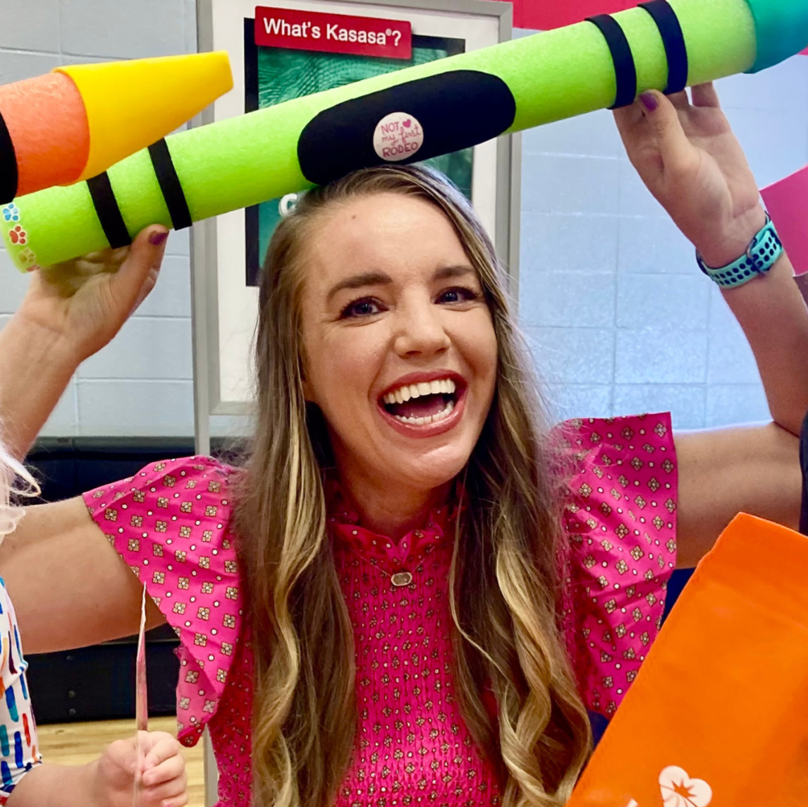 A woman is holding a crayon over her head and smiling