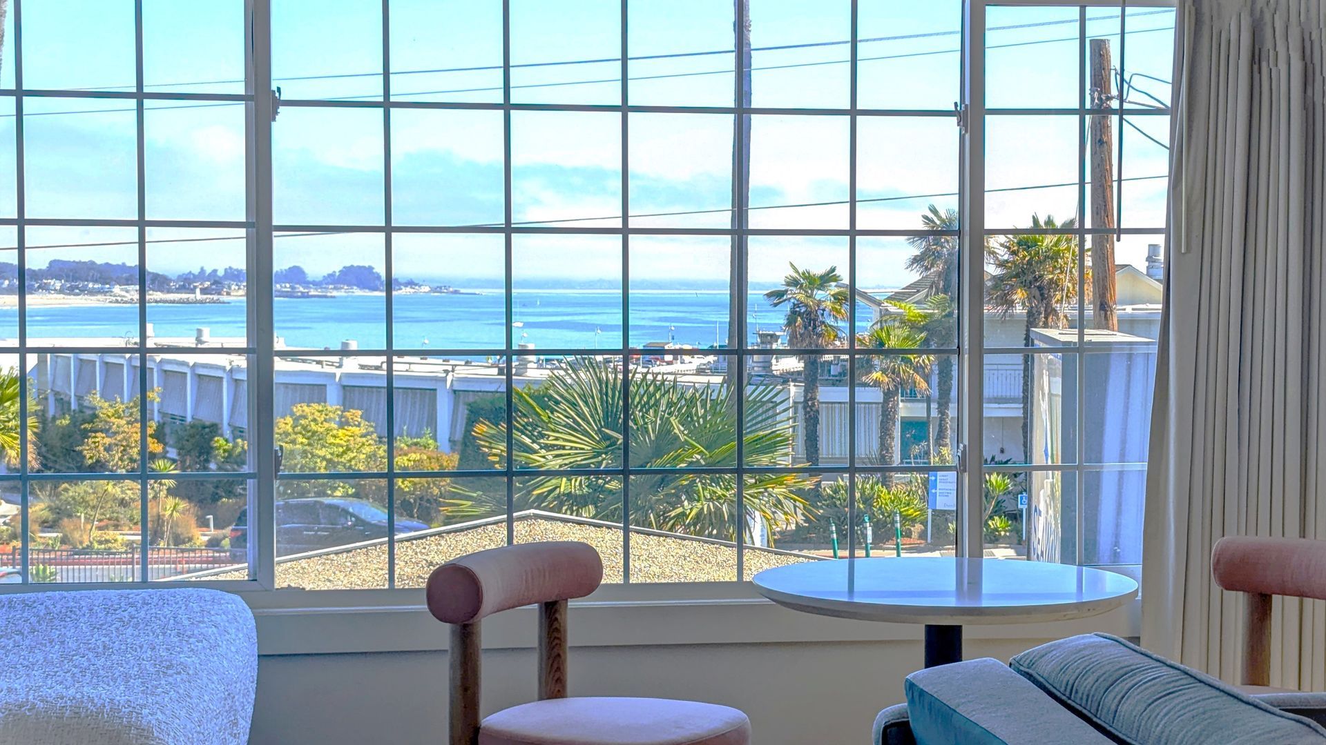 Table in and chairs in front of open window with view of the ocean 