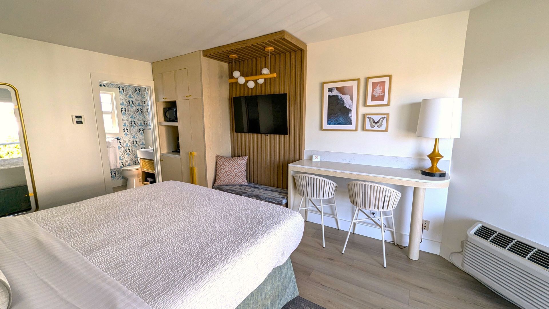 Foot of bed with TV and counter with chairs behind it