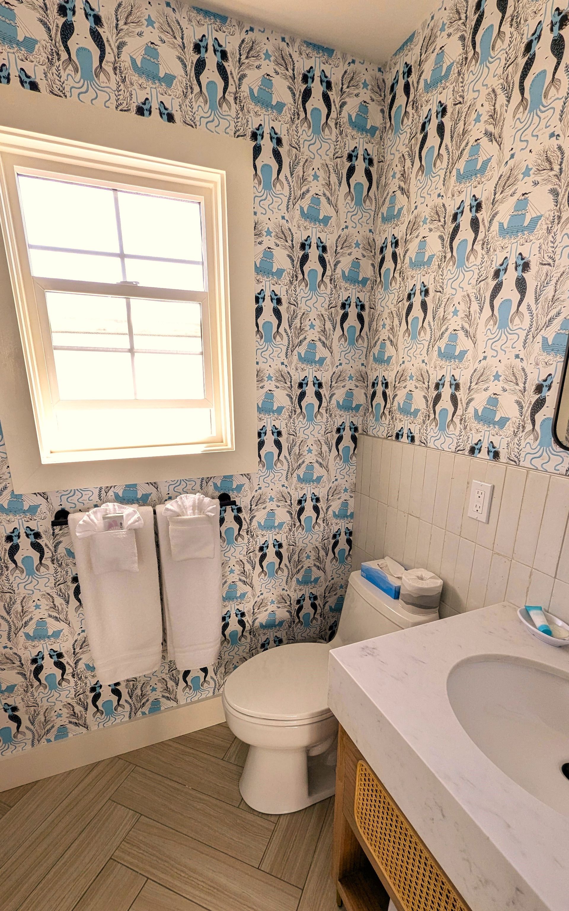 Bathroom with toilet, sink, and mermaid wallpaper