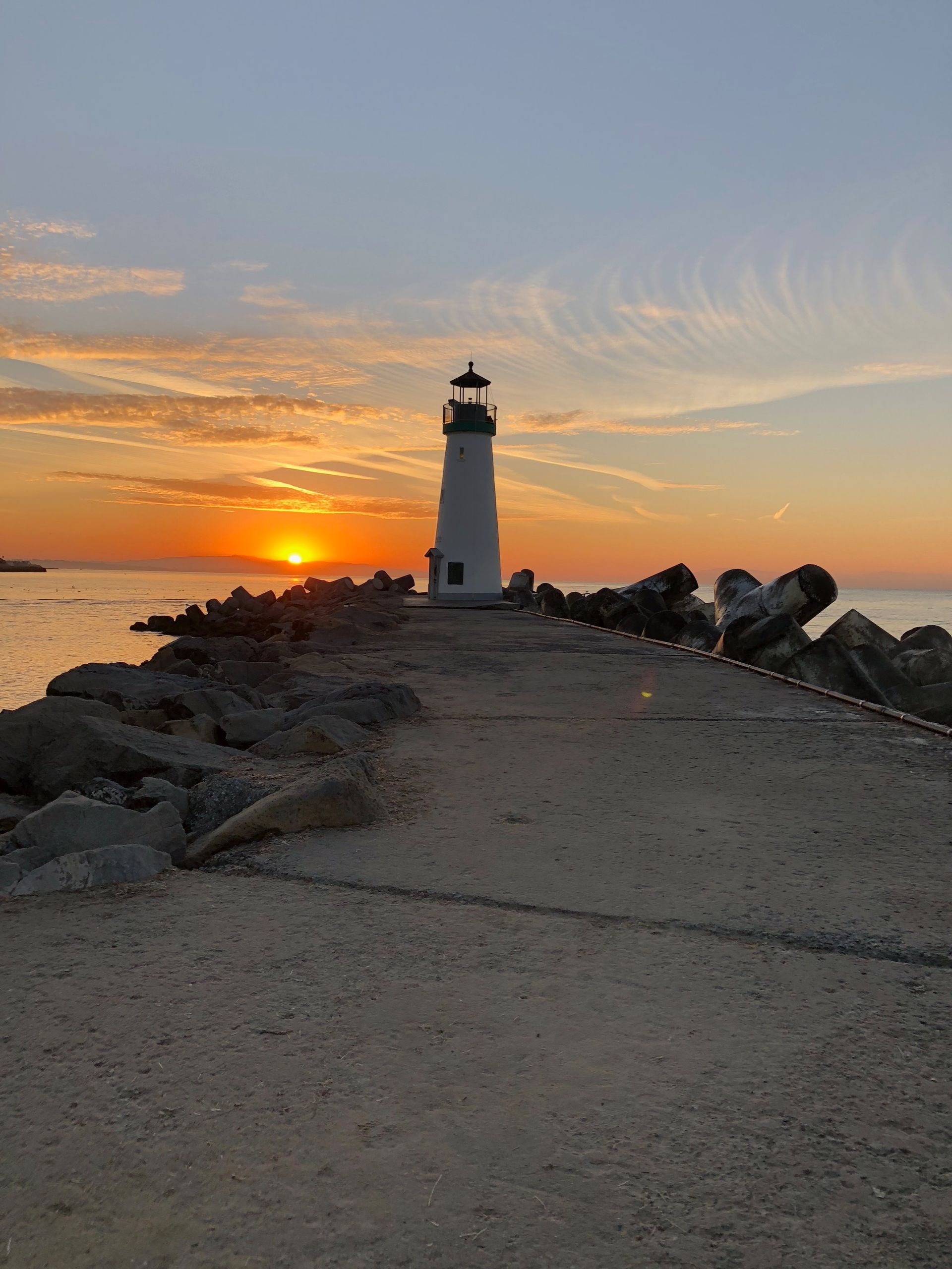 view of lighthouse at sunset that's straight ahead on a path