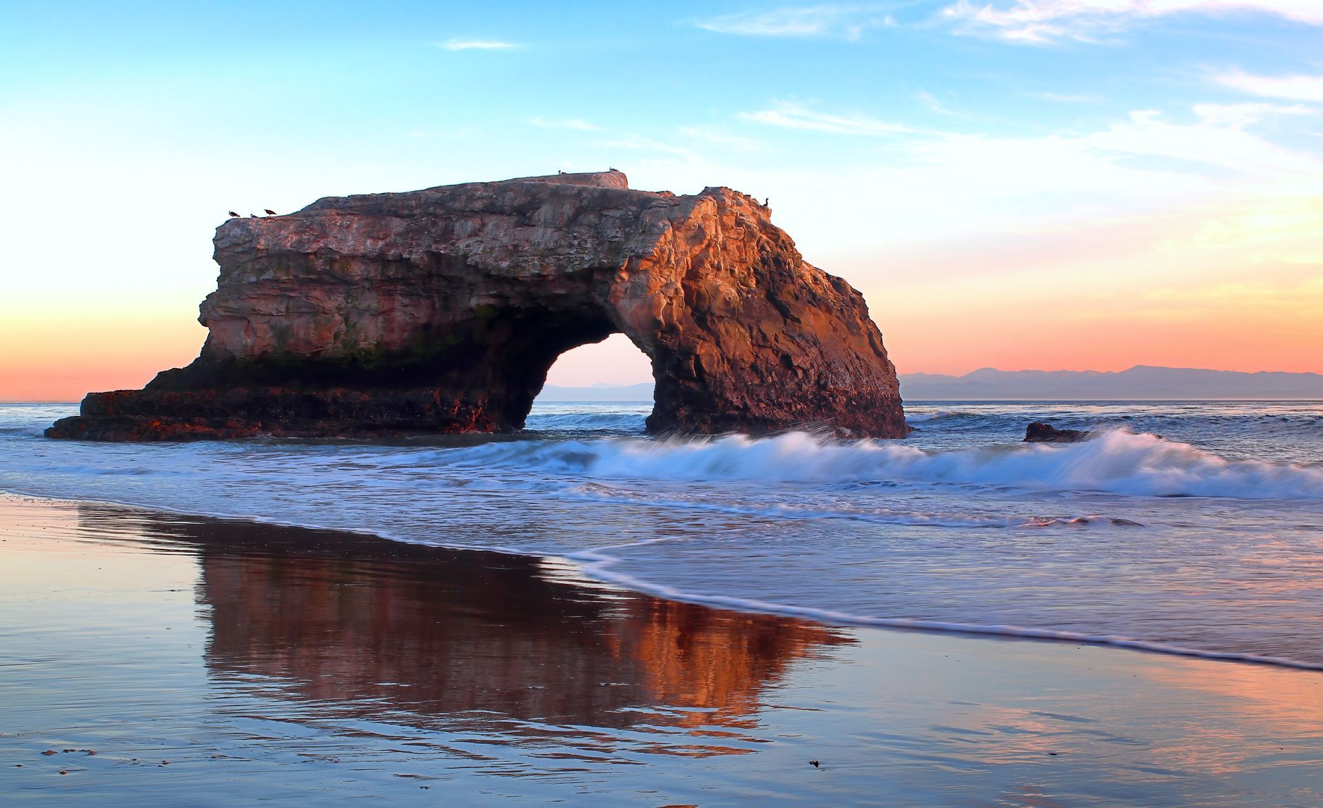 one of the natural bridge formations near the shore with waves surrounding it