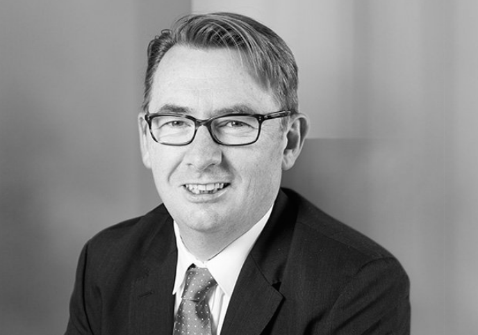 A man in a suit and tie is smiling in a black and white photo.