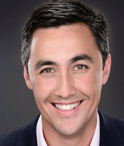 A man in a suit and white shirt is smiling for the camera.