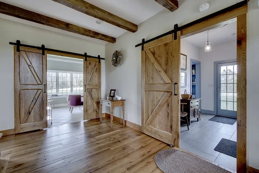 Hallway with wooden sliding barn doors, hardwood floors, and views into a living area and a bright entryway.