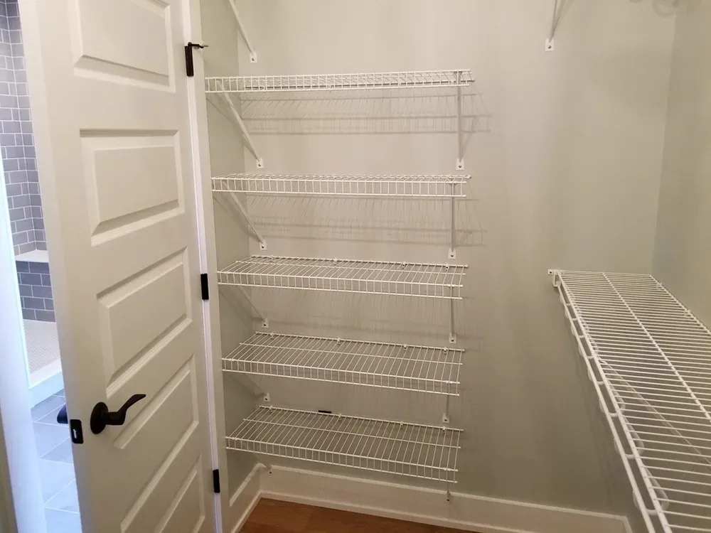 White wire shelving installed inside a closet next to an open interior door.