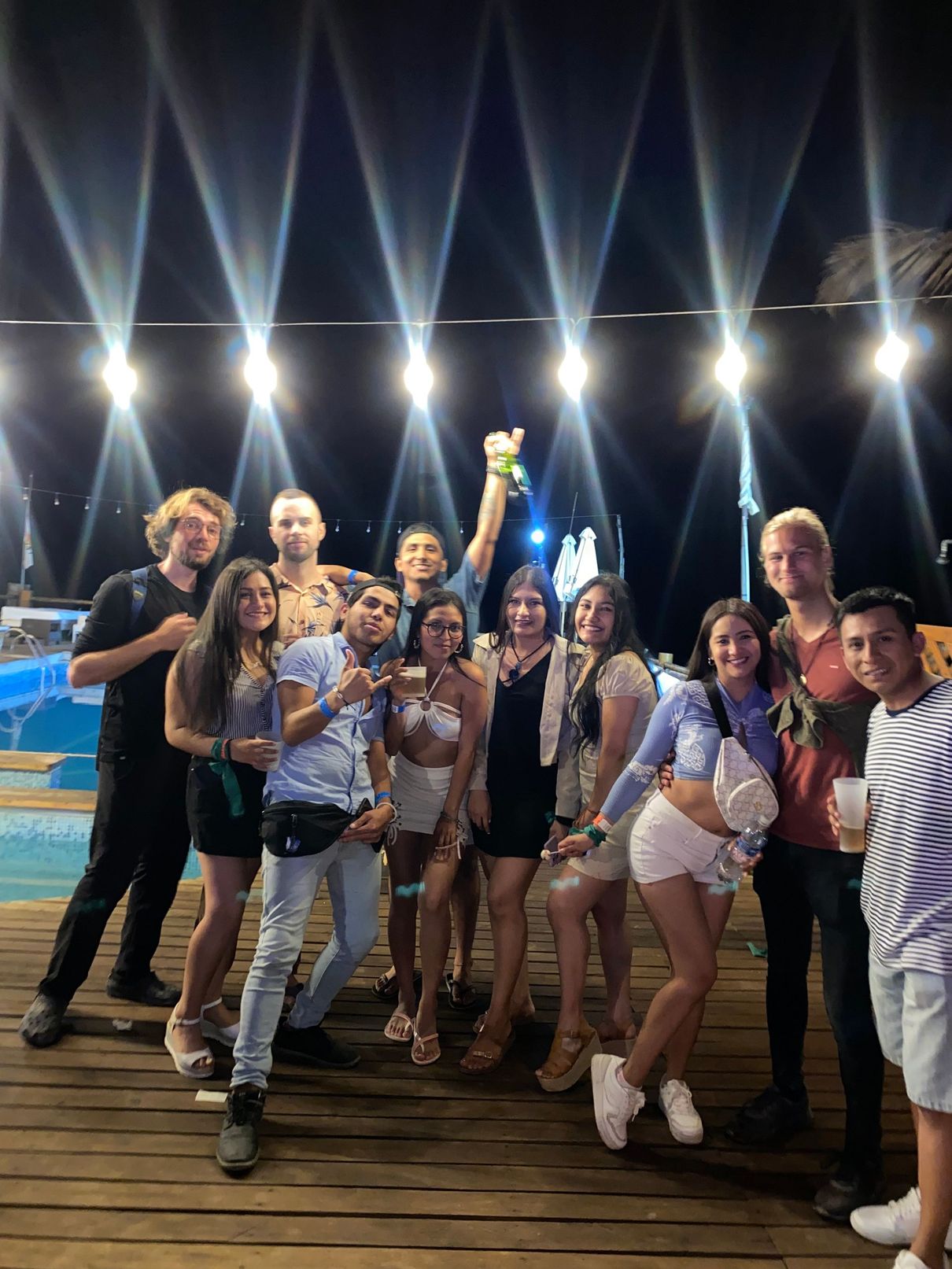 A group of people are posing for a picture on a pier at night.