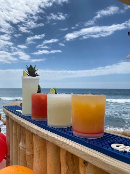 A row of drinks sitting on a bar next to the ocean