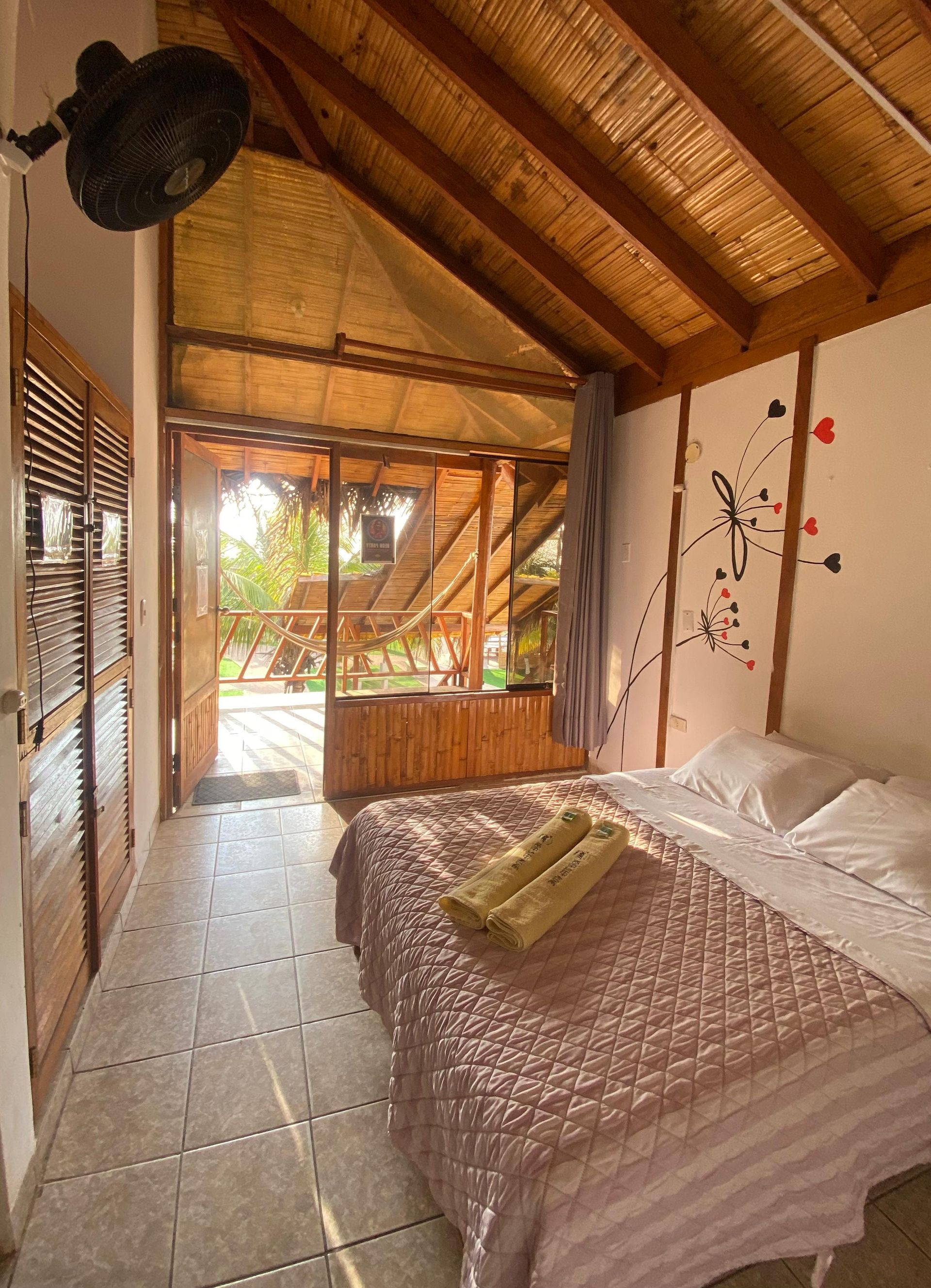 A bedroom with a bed and a fan on the ceiling.