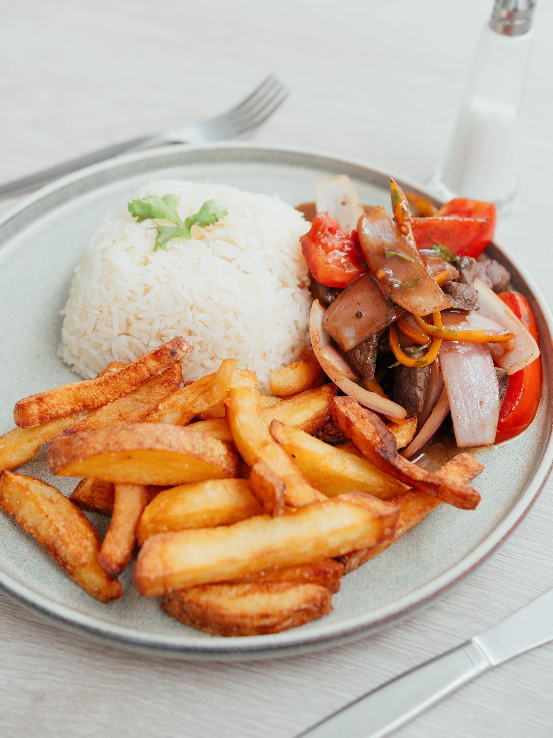 A plate of food with rice and french fries on a table.