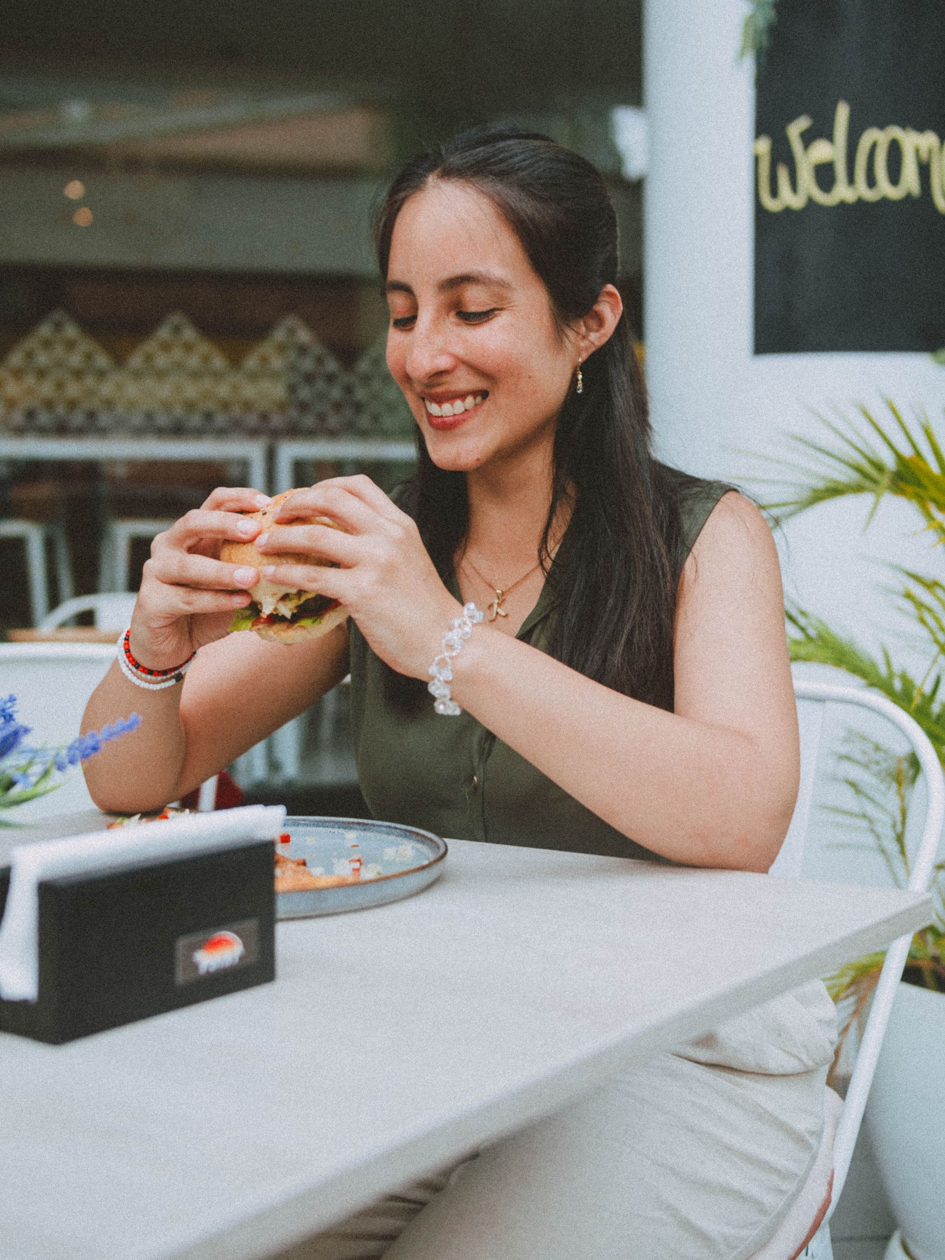 A woman is sitting at a table eating a sandwich